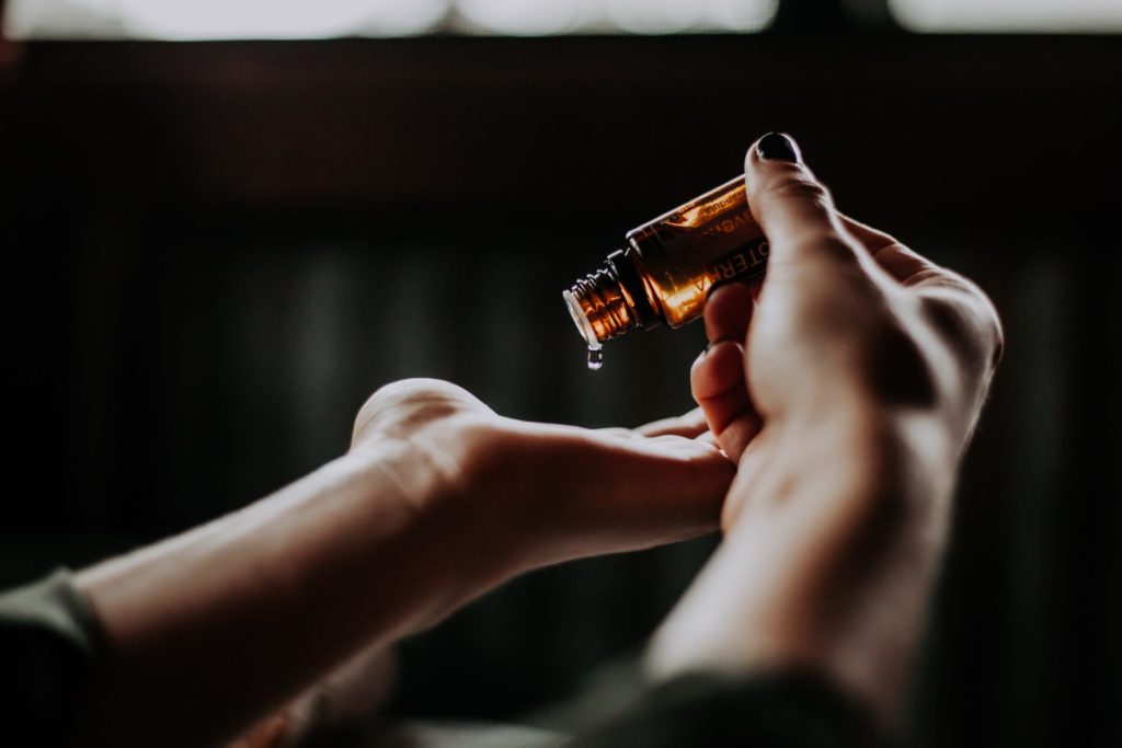 Hands pouring out a drop of essential oils
