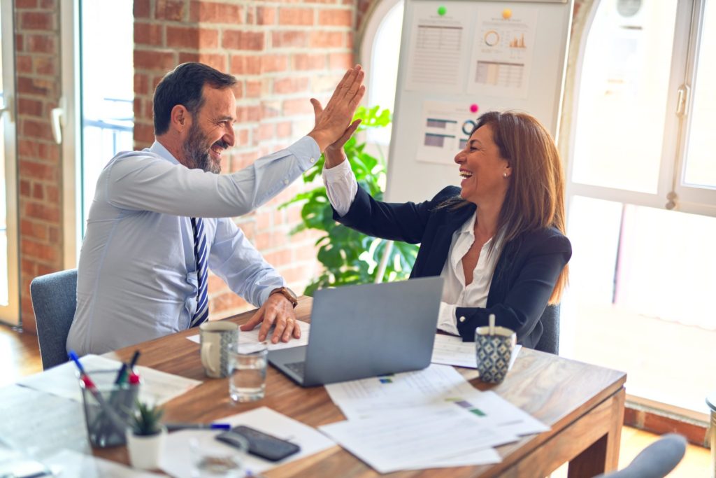 Man and Woman Giving High Five in Office